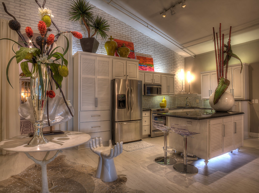 Modern inredning av ett kök, med en undermonterad diskho, luckor med lamellpanel, vita skåp, granitbänkskiva, stänkskydd i glaskakel, rostfria vitvaror, målat trägolv och en köksö
