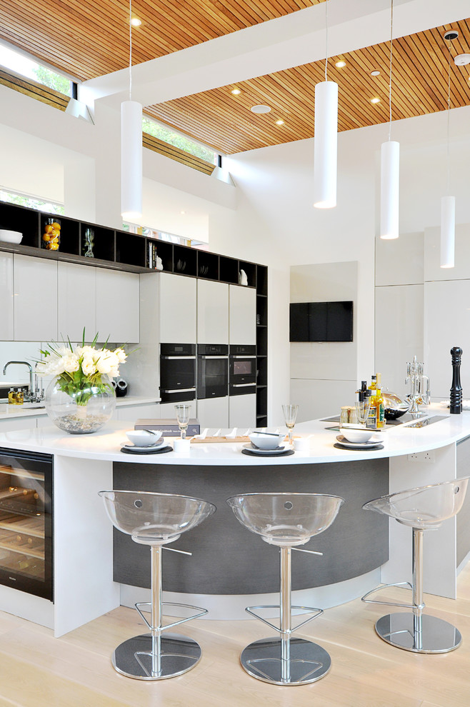 Пример оригинального дизайна: глянцевая кухня-гостиная в современном стиле с плоскими фасадами, серыми фасадами, светлым паркетным полом и телевизором