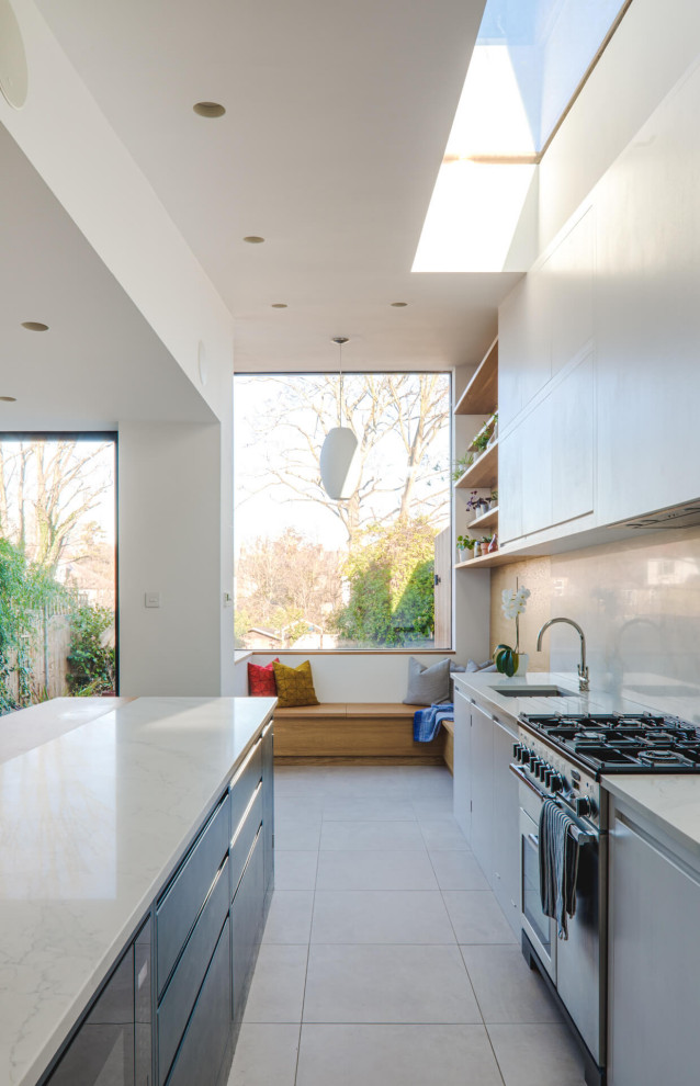 Design ideas for a large contemporary single-wall open plan kitchen in London with a built-in sink, flat-panel cabinets, white cabinets, quartz worktops, white splashback, stone slab splashback, stainless steel appliances, ceramic flooring, an island, white floors and white worktops.