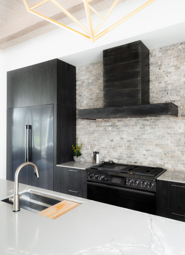 Medium sized contemporary single-wall kitchen in Houston with flat-panel cabinets, grey splashback, multiple islands, black appliances, beige floors, white worktops, exposed beams, a submerged sink, black cabinets and stone tiled splashback.