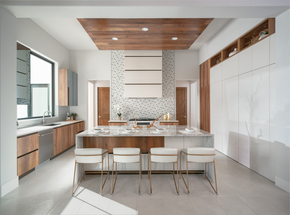 Cette image montre une cuisine bicolore design en U et bois brun avec un évier encastré, un placard à porte plane, un électroménager en acier inoxydable, îlot, un sol gris et un plan de travail gris.
