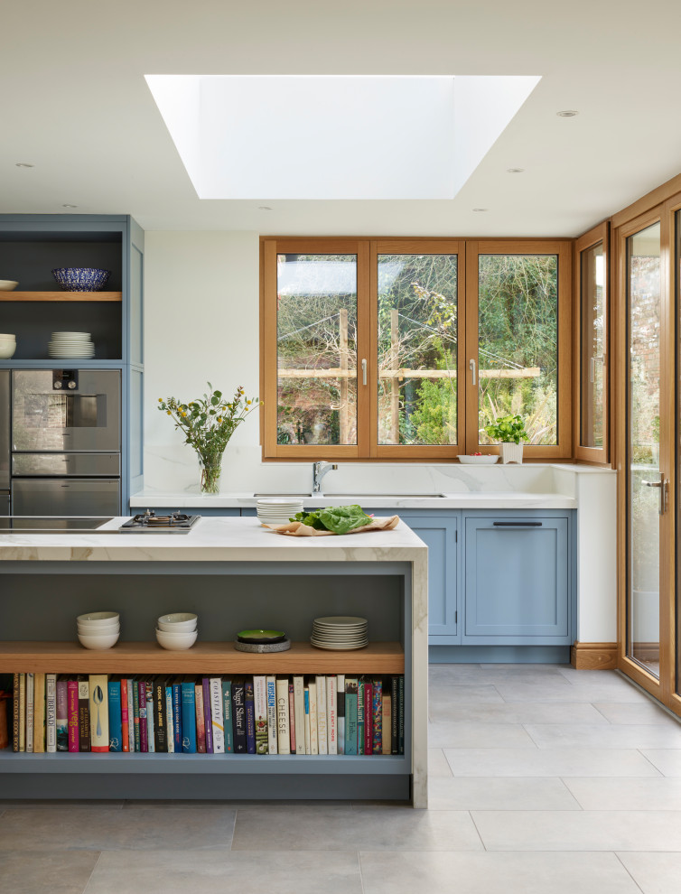 Immagine di una grande cucina chic con lavello sottopiano, ante in stile shaker, ante blu, elettrodomestici in acciaio inossidabile, pavimento in gres porcellanato, pavimento grigio e top bianco