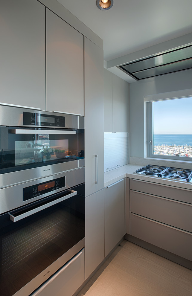 Example of a mid-sized trendy galley light wood floor eat-in kitchen design in San Francisco with an undermount sink, flat-panel cabinets, gray cabinets, quartzite countertops, stainless steel appliances and a peninsula