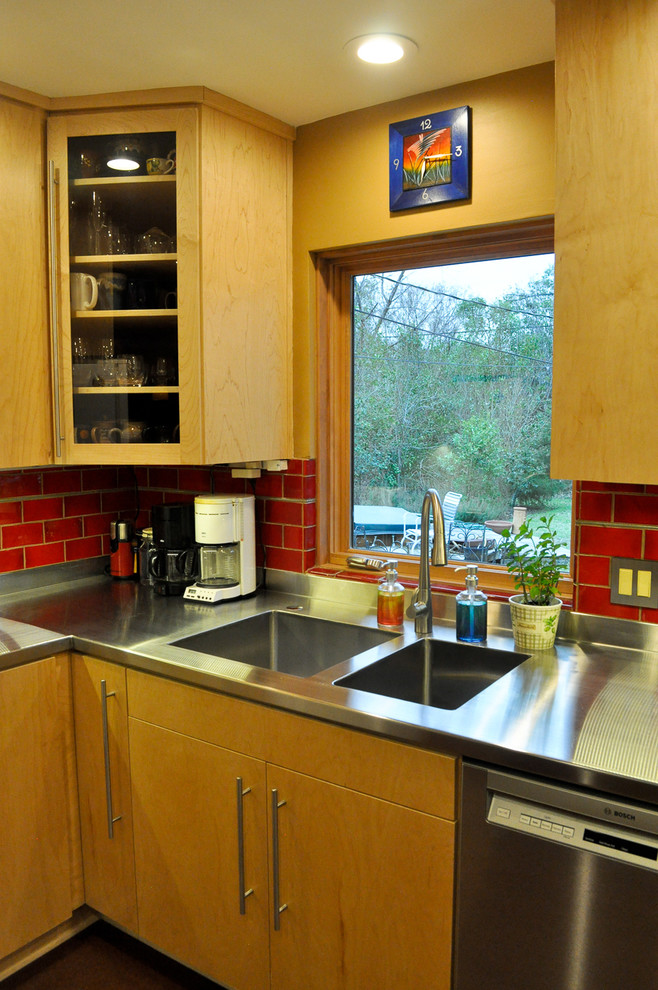 Idéer för att renovera ett litet funkis kök, med en integrerad diskho, släta luckor, skåp i ljust trä, bänkskiva i rostfritt stål, rött stänkskydd, stänkskydd i keramik, rostfria vitvaror och korkgolv