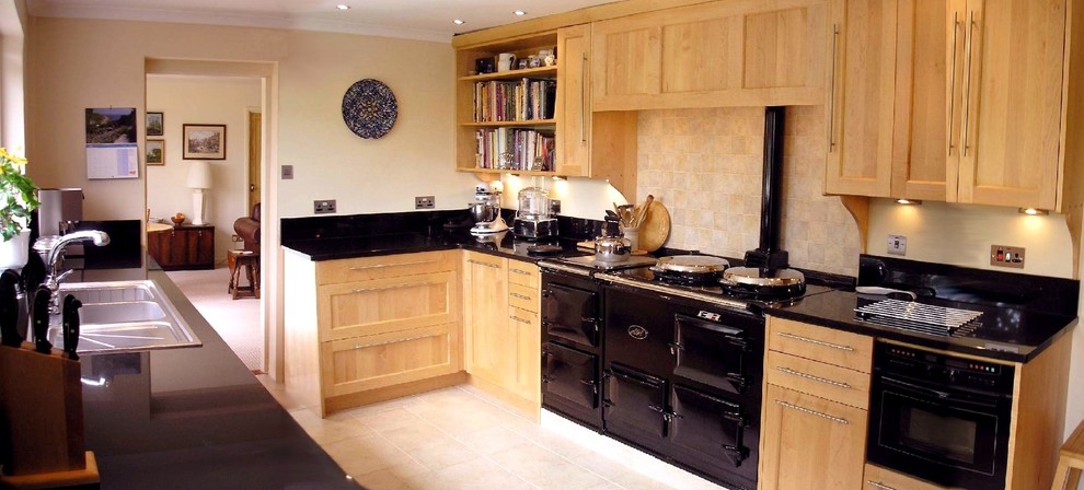 Foto di una grande cucina ad U design chiusa con lavello a doppia vasca, ante in legno chiaro, top in granito, elettrodomestici neri e pavimento in travertino