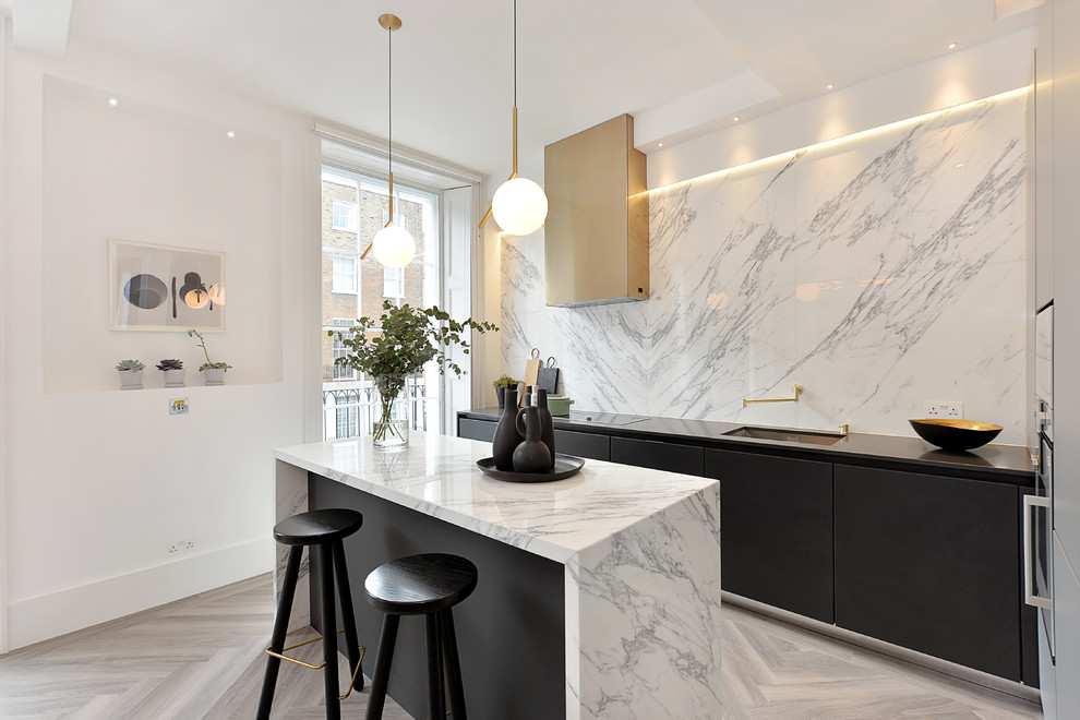 Idee per un cucina con isola centrale minimal con lavello sottopiano, ante lisce, top in marmo, paraspruzzi bianco, parquet chiaro e pavimento beige