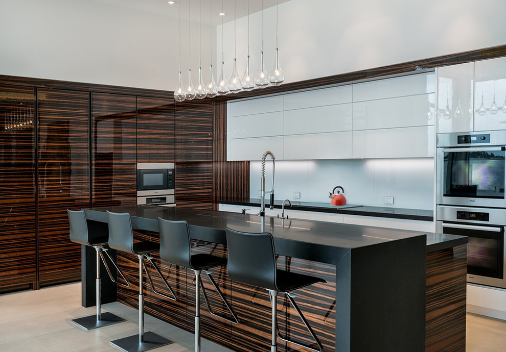Immagine di un cucina con isola centrale design con ante lisce, ante bianche, paraspruzzi bianco e elettrodomestici in acciaio inossidabile