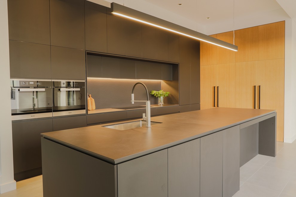 Foto på ett mellanstort funkis svart kök, med en undermonterad diskho, luckor med infälld panel, svarta skåp, bänkskiva i kvarts, svart stänkskydd, stänkskydd i sten, rostfria vitvaror, cementgolv, en köksö och grått golv