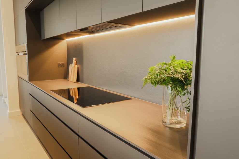 Inspiration for a medium sized contemporary galley kitchen/diner in Sydney with a submerged sink, recessed-panel cabinets, black cabinets, engineered stone countertops, black splashback, stone slab splashback, stainless steel appliances, cement flooring, an island, grey floors and black worktops.