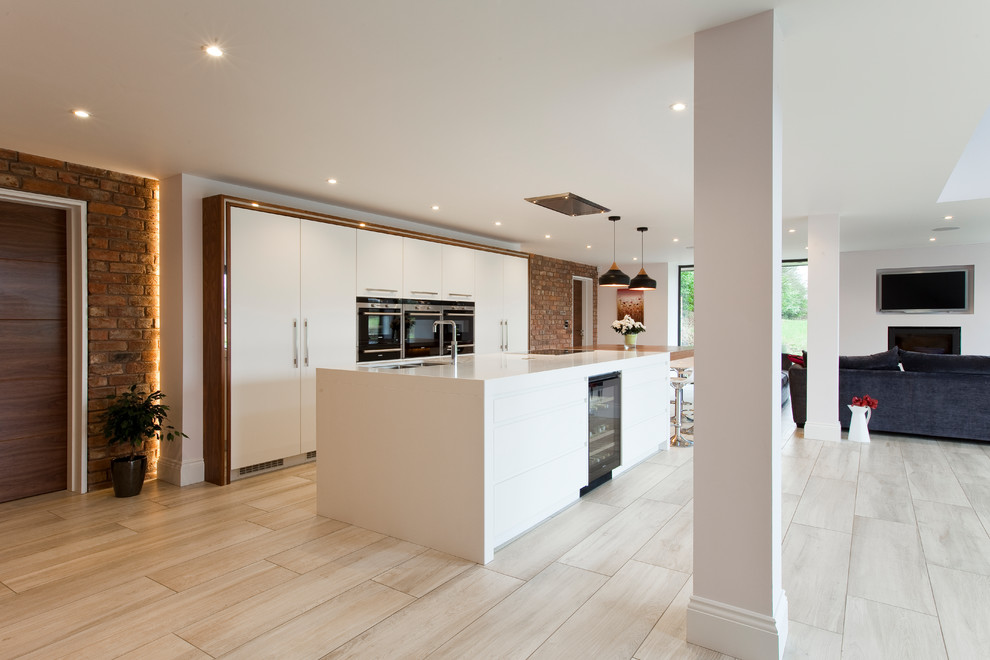 Inspiration for a large contemporary galley open plan kitchen in Cheshire with a submerged sink, flat-panel cabinets, white cabinets, quartz worktops, stainless steel appliances, porcelain flooring and an island.