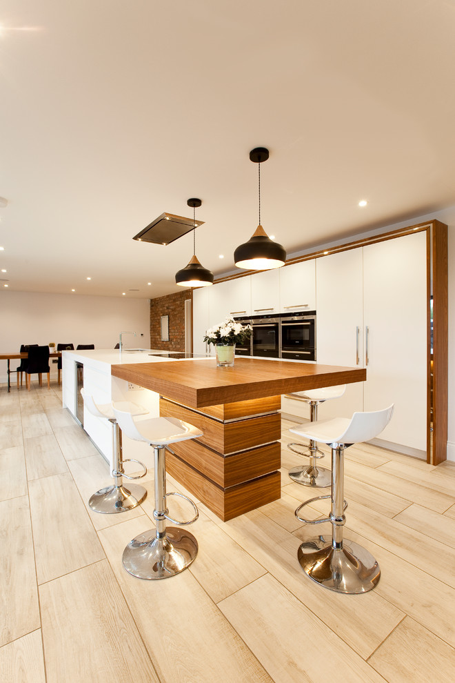 Inspiration for a large contemporary galley open plan kitchen in Cheshire with a submerged sink, flat-panel cabinets, white cabinets, quartz worktops, stainless steel appliances, porcelain flooring and an island.