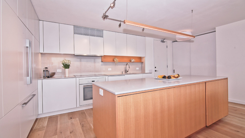 Example of a mid-sized trendy l-shaped light wood floor and beige floor eat-in kitchen design in Chicago with a single-bowl sink, flat-panel cabinets, white cabinets, quartzite countertops, gray backsplash, stone slab backsplash, paneled appliances and an island