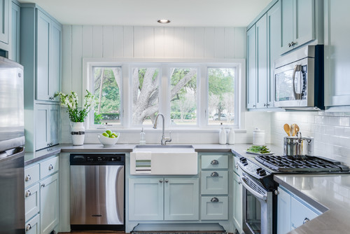Cabinet color trends with soft pastel blue kitchen cabinets, farmhouse sink, and bright natural light for a refreshing look.