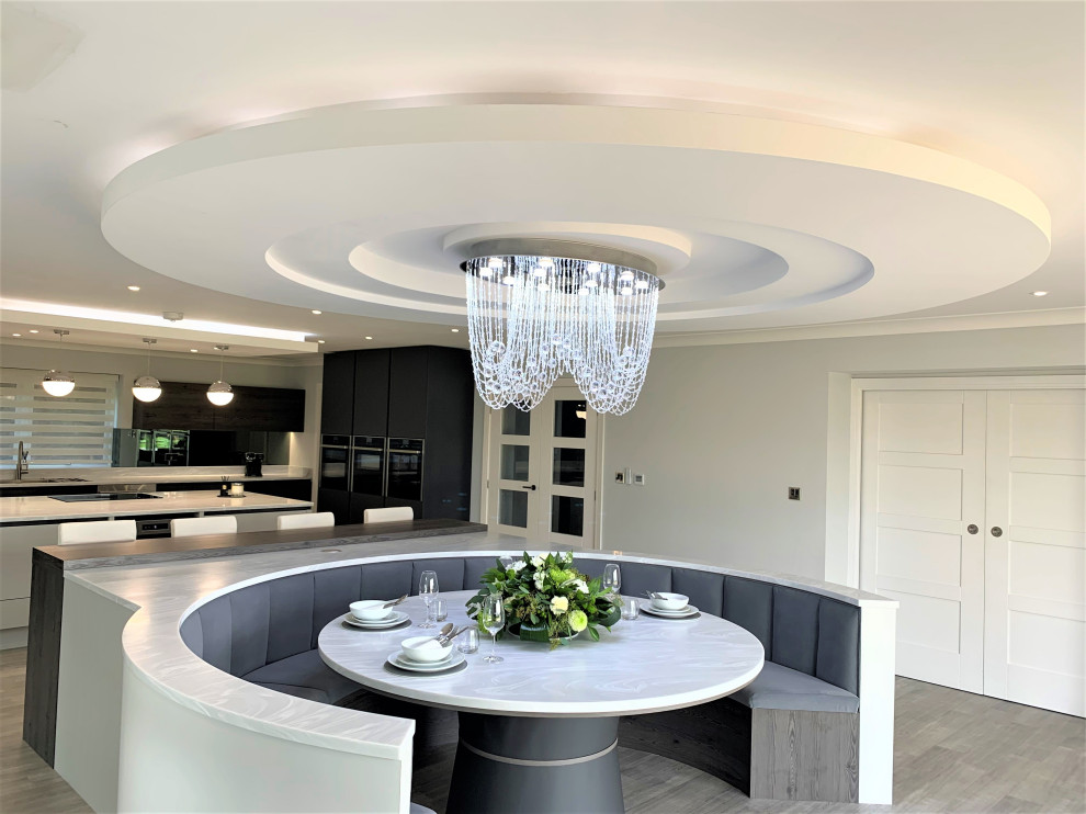 Design ideas for a large contemporary u-shaped open plan kitchen in Other with a double-bowl sink, medium wood cabinets, composite countertops, glass sheet splashback, black appliances, an island, white worktops and a drop ceiling.