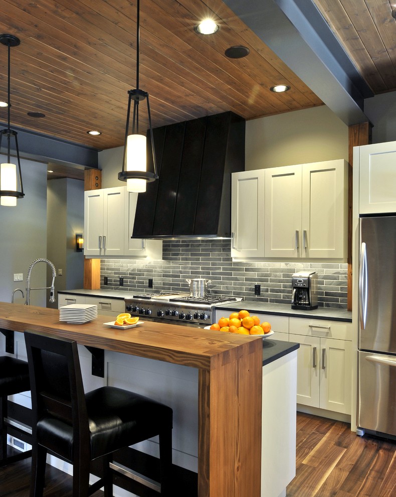 Example of a trendy kitchen design in Seattle with shaker cabinets, white cabinets, gray backsplash, stone tile backsplash and stainless steel appliances