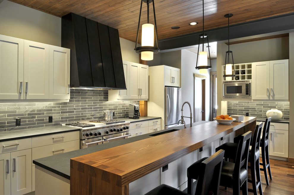 Offene Moderne Küche in L-Form mit Waschbecken, Schrankfronten im Shaker-Stil, weißen Schränken, Rückwand aus Steinfliesen und Küchengeräten aus Edelstahl in Seattle