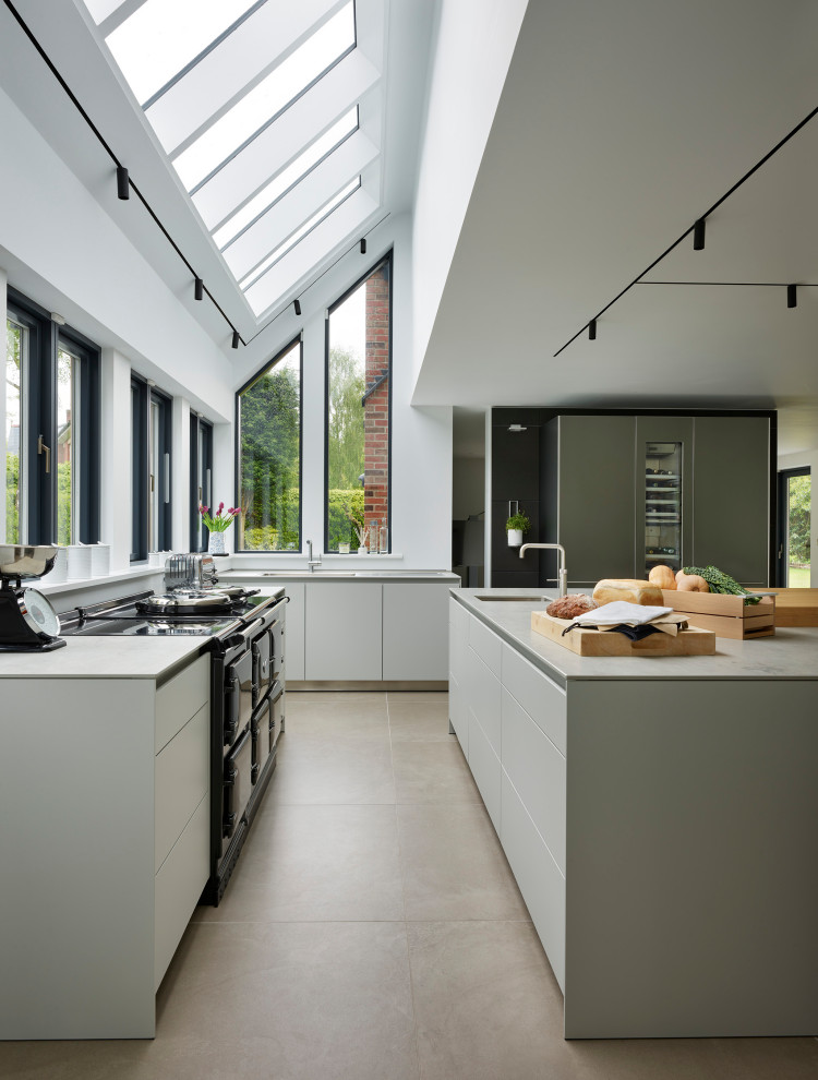Свежая идея для дизайна: угловая кухня в современном стиле с врезной мойкой, плоскими фасадами, серыми фасадами, островом, серым полом и серой столешницей - отличное фото интерьера