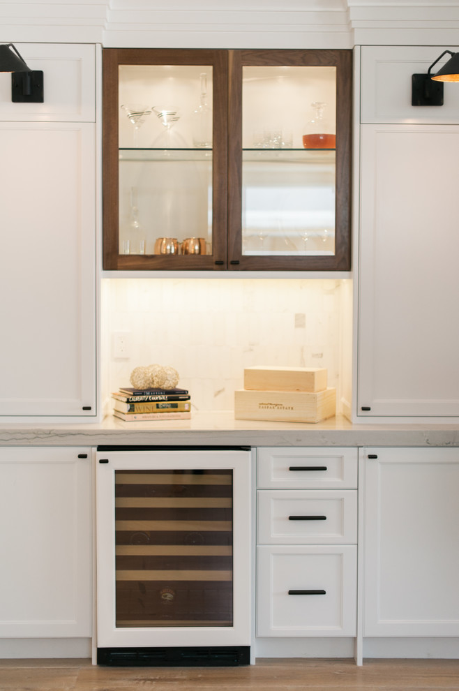 Open concept kitchen - contemporary u-shaped light wood floor open concept kitchen idea in Orange County with an undermount sink, shaker cabinets, white cabinets, quartzite countertops, white backsplash, stone tile backsplash, white appliances and an island