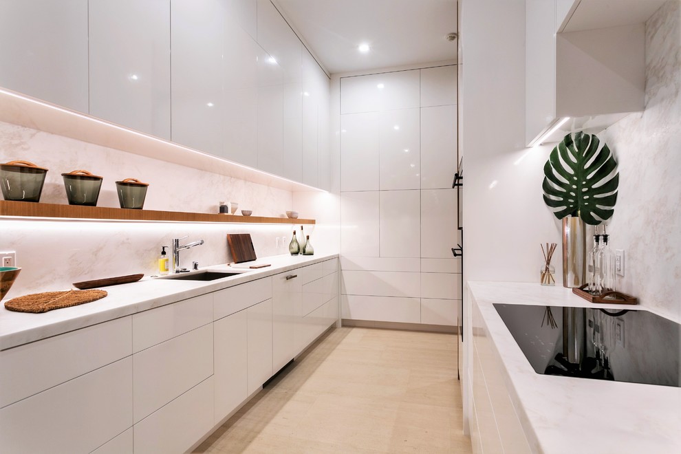 Example of a mid-sized trendy u-shaped beige floor eat-in kitchen design in Orange County with flat-panel cabinets, marble countertops, white backsplash, stone slab backsplash, an undermount sink, white cabinets, white countertops and no island