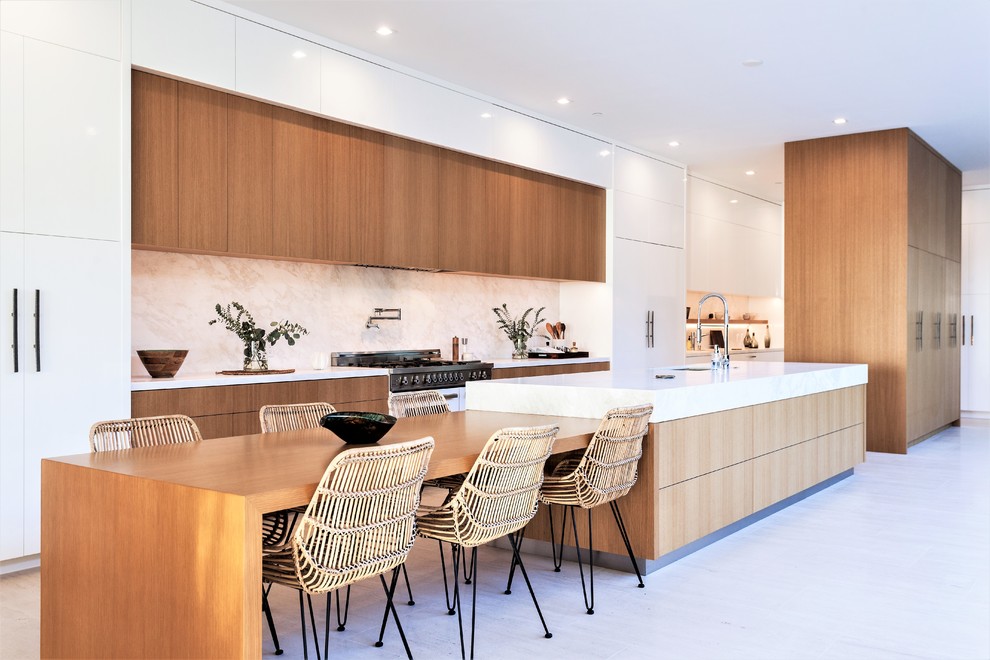 Inspiration for a large contemporary galley kitchen/diner in Orange County with a submerged sink, flat-panel cabinets, medium wood cabinets, marble worktops, white splashback, stone slab splashback, an island, beige floors, white worktops and integrated appliances.