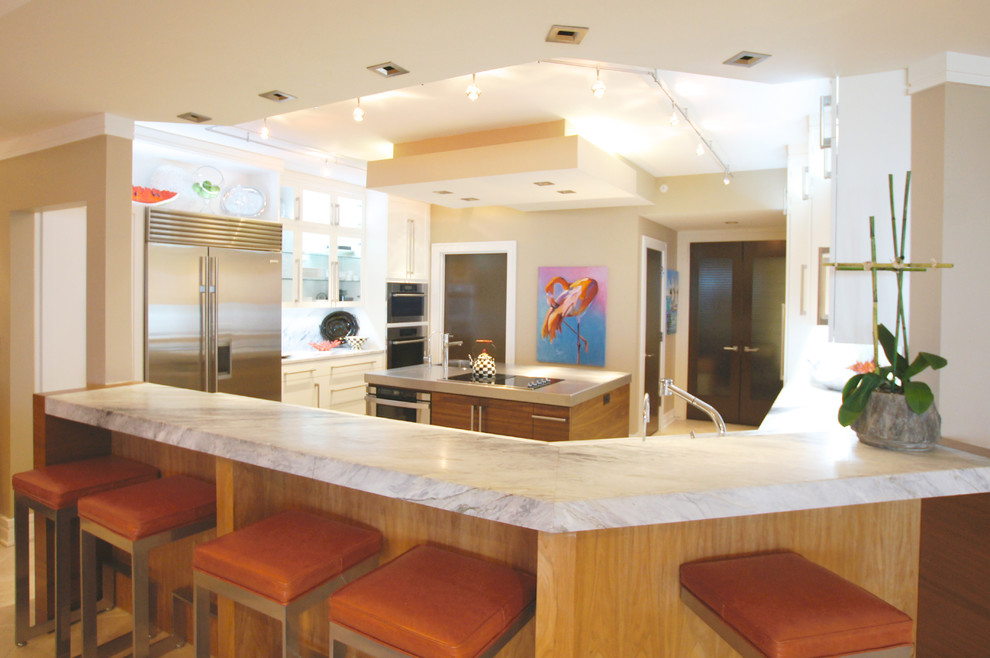 ジャクソンビルにある高級な広いコンテンポラリースタイルのおしゃれなキッチン (シェーカースタイル扉のキャビネット、白いキャビネット、ステンレスカウンター、白いキッチンパネル、大理石のキッチンパネル、シルバーの調理設備、アンダーカウンターシンク、磁器タイルの床、ベージュの床、白いキッチンカウンター) の写真