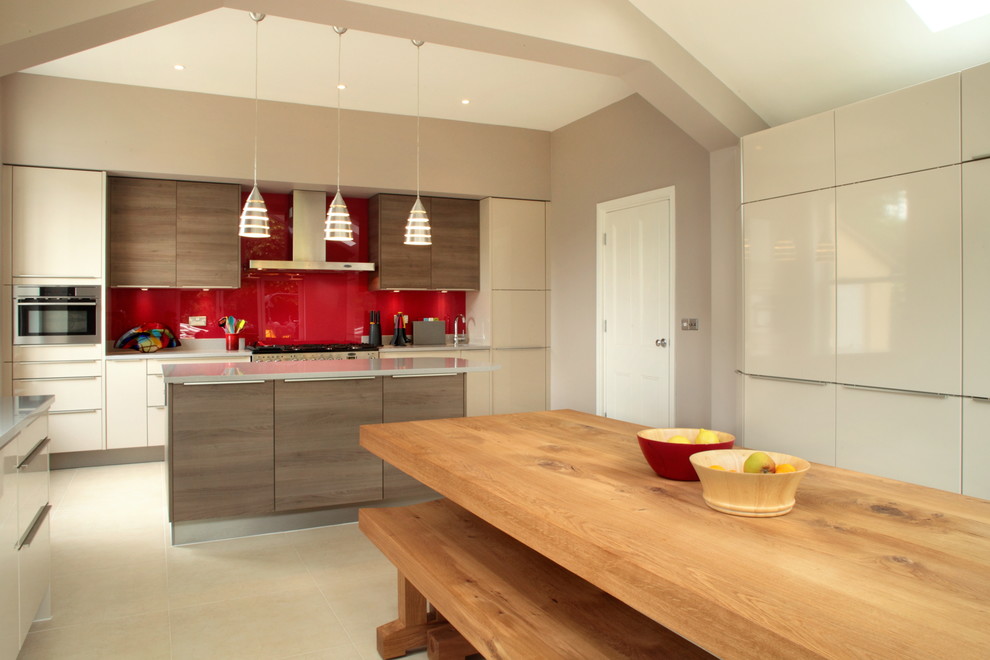 This is an example of a large contemporary u-shaped open plan kitchen in Buckinghamshire with quartz worktops, red splashback, glass tiled splashback, stainless steel appliances and an island.