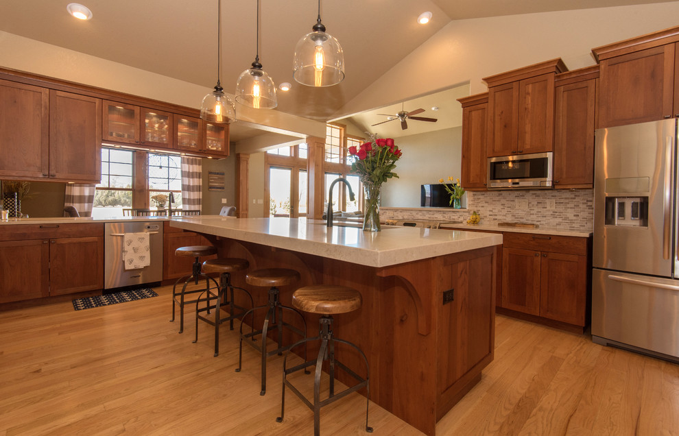 Large traditional single-wall kitchen/diner in Denver with a submerged sink, shaker cabinets, dark wood cabinets, engineered stone countertops, multi-coloured splashback, matchstick tiled splashback, stainless steel appliances, light hardwood flooring, an island and brown floors.