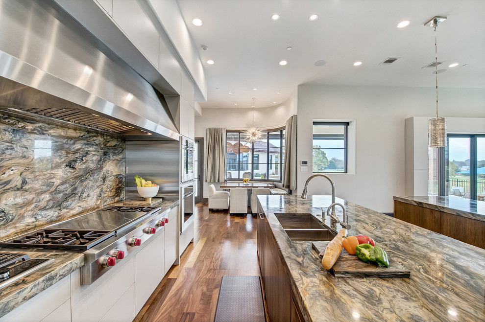 Example of a large trendy galley medium tone wood floor and brown floor eat-in kitchen design in Orange County with an undermount sink, flat-panel cabinets, gray cabinets, quartzite countertops, multicolored backsplash, stone slab backsplash, stainless steel appliances and two islands