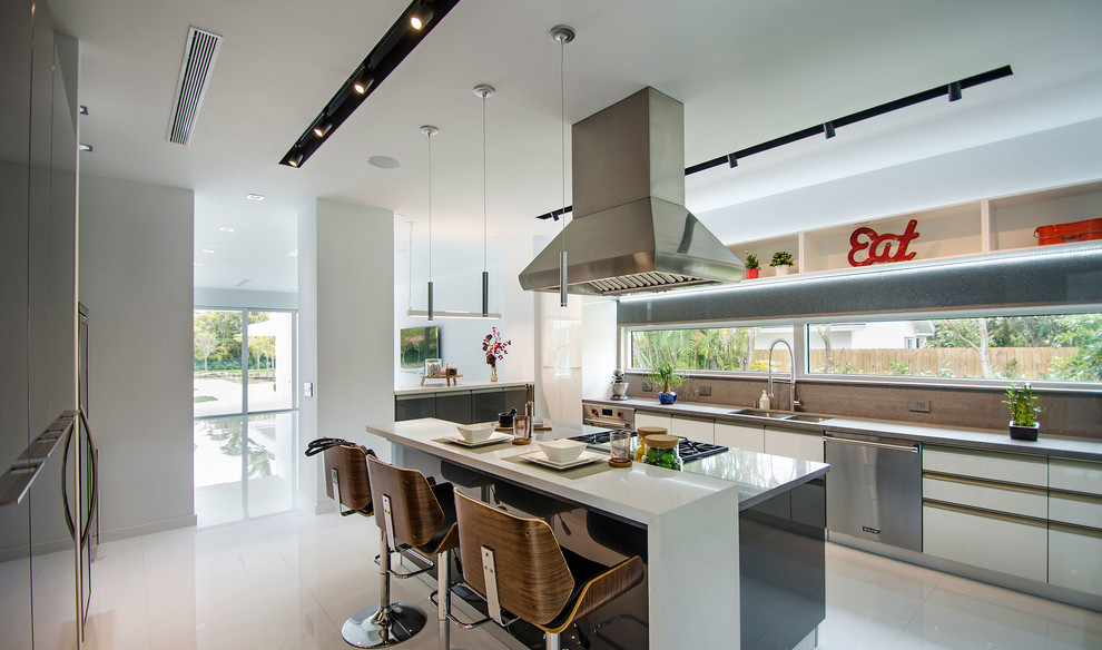 Design ideas for a large modern l-shaped enclosed kitchen in Miami with flat-panel cabinets, white cabinets, window splashback, an island, a double-bowl sink, stainless steel appliances, porcelain flooring, white floors and engineered stone countertops.