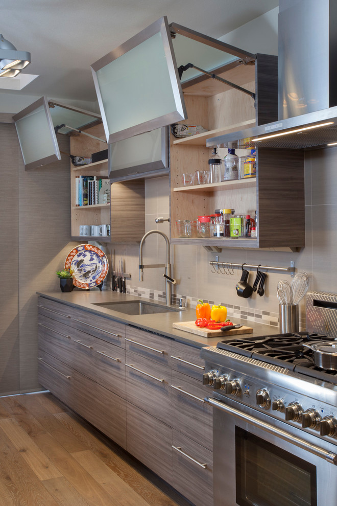 Moderne Küche mit Unterbauwaschbecken, Glasfronten, Küchenrückwand in Grau, Küchengeräten aus Edelstahl, braunem Holzboden und grauer Arbeitsplatte in San Diego