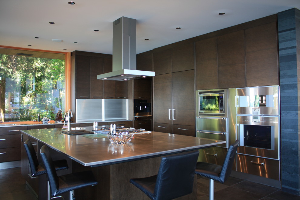 This is an example of an expansive contemporary u-shaped open plan kitchen in Vancouver with a submerged sink, flat-panel cabinets, dark wood cabinets, engineered stone countertops, stainless steel appliances, porcelain flooring and an island.