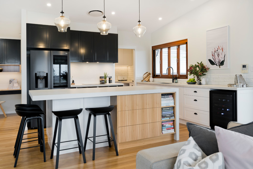 Design ideas for a large contemporary u-shaped open plan kitchen in Brisbane with a submerged sink, white cabinets, engineered stone countertops, white splashback, metro tiled splashback, black appliances, light hardwood flooring, an island, white worktops, shaker cabinets and beige floors.