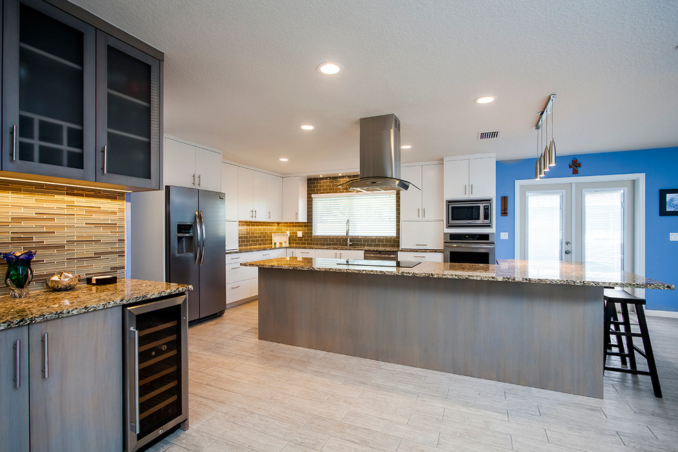 Contemporary l-shaped open plan kitchen in Tampa with a submerged sink, flat-panel cabinets, glass tiled splashback, stainless steel appliances, ceramic flooring and an island.