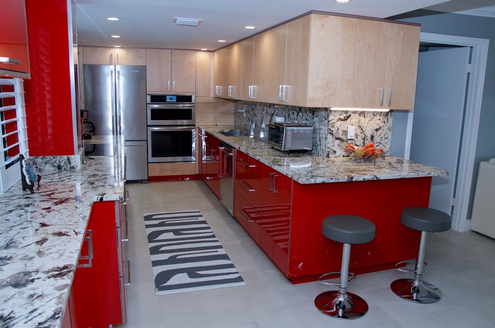 Inredning av ett modernt stort parallellkök, med en undermonterad diskho, släta luckor, röda skåp, granitbänkskiva, rostfria vitvaror och en halv köksö