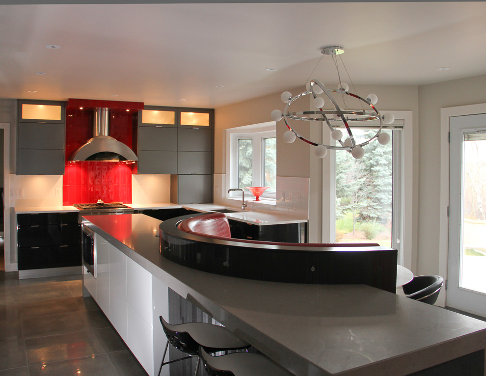 Large contemporary u-shaped kitchen in Calgary with a submerged sink, flat-panel cabinets, engineered stone countertops, red splashback, glass tiled splashback, integrated appliances, porcelain flooring and an island.