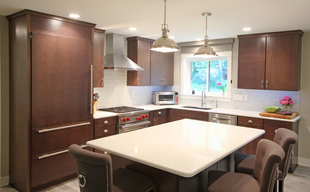 This is an example of a small modern l-shaped kitchen/diner in Grand Rapids with a submerged sink, flat-panel cabinets, brown cabinets, engineered stone countertops, white splashback, metro tiled splashback, stainless steel appliances, light hardwood flooring and an island.