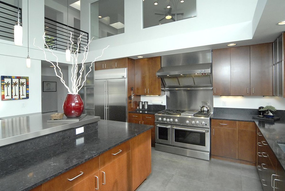 Exempel på ett mellanstort modernt kök, med en undermonterad diskho, luckor med glaspanel, skåp i mellenmörkt trä, bänkskiva i rostfritt stål, rostfria vitvaror, klinkergolv i porslin, en köksö och grått golv