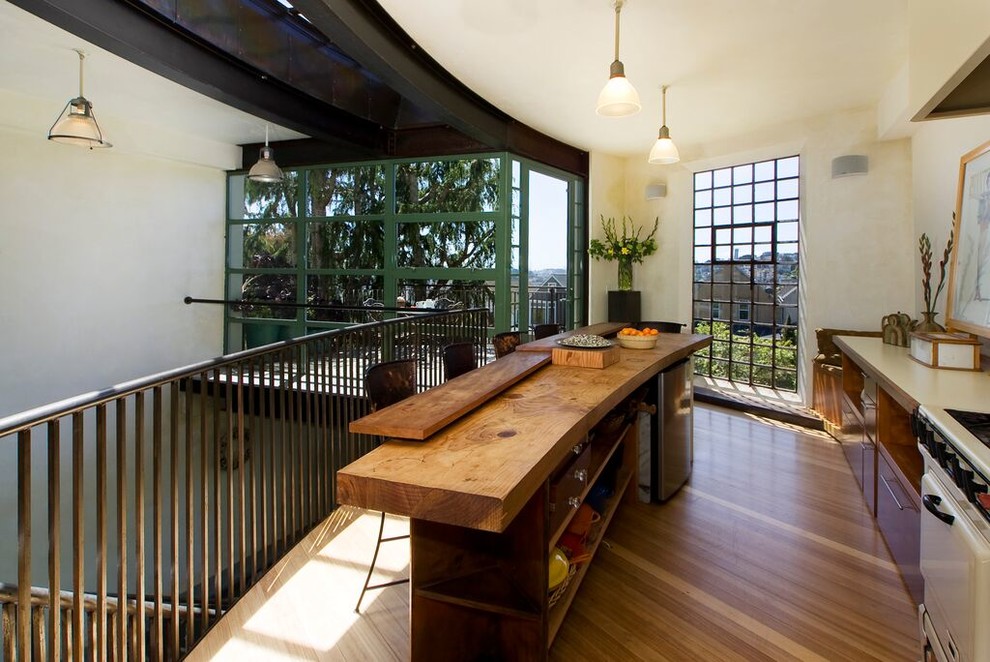 Foto på ett mellanstort funkis linjärt kök och matrum, med träbänkskiva, vita vitvaror, en köksö, en undermonterad diskho, släta luckor, bambugolv och brunt golv