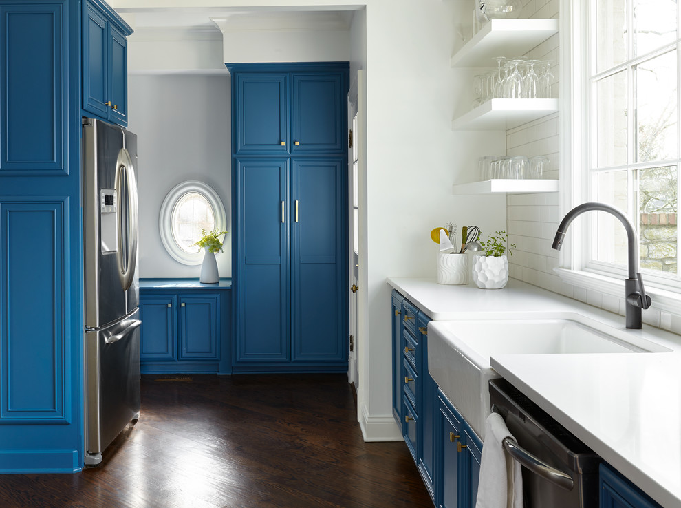 Foto di una cucina classica con lavello stile country, ante con riquadro incassato, ante blu, paraspruzzi bianco, elettrodomestici in acciaio inossidabile, parquet scuro e pavimento marrone
