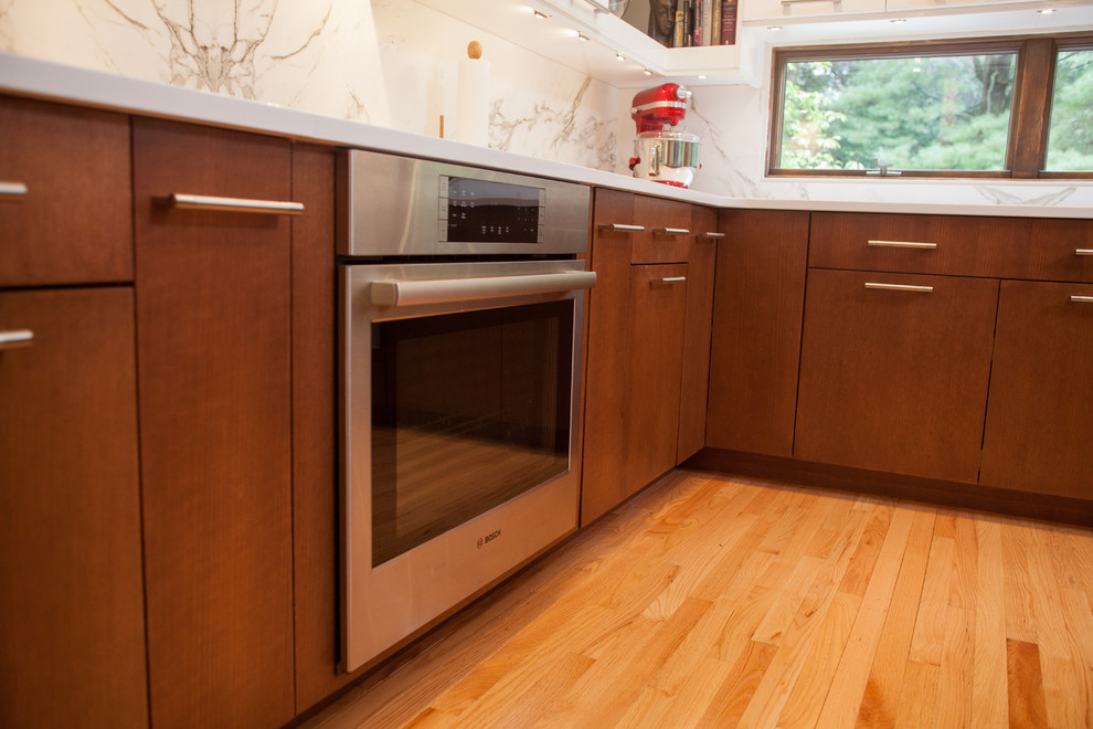 Modern inredning av ett mellanstort kök, med en rustik diskho, släta luckor, vita skåp, bänkskiva i kvarts, vitt stänkskydd, stänkskydd i sten, rostfria vitvaror, ljust trägolv och en köksö