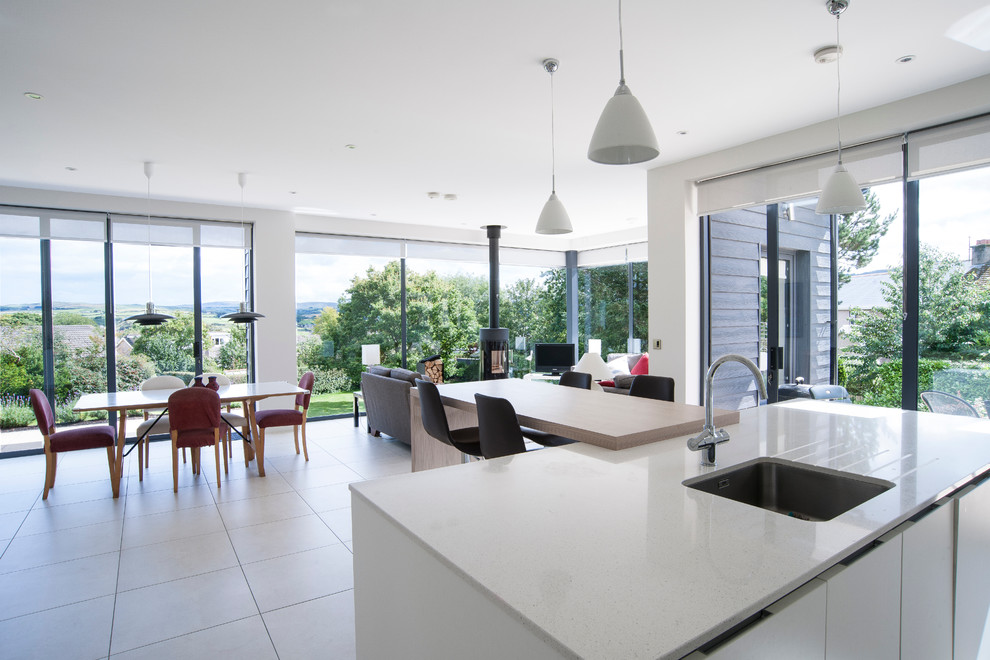 Photo of a medium sized contemporary single-wall open plan kitchen in London with an integrated sink, flat-panel cabinets, white cabinets, marble worktops, white splashback, stone slab splashback, integrated appliances, ceramic flooring and an island.