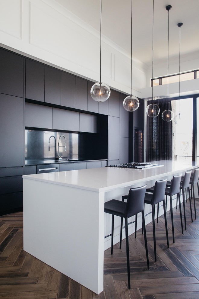 Photo of a contemporary galley kitchen in Omaha with a submerged sink, flat-panel cabinets, black cabinets, black splashback, medium hardwood flooring, an island, brown floors and white worktops.