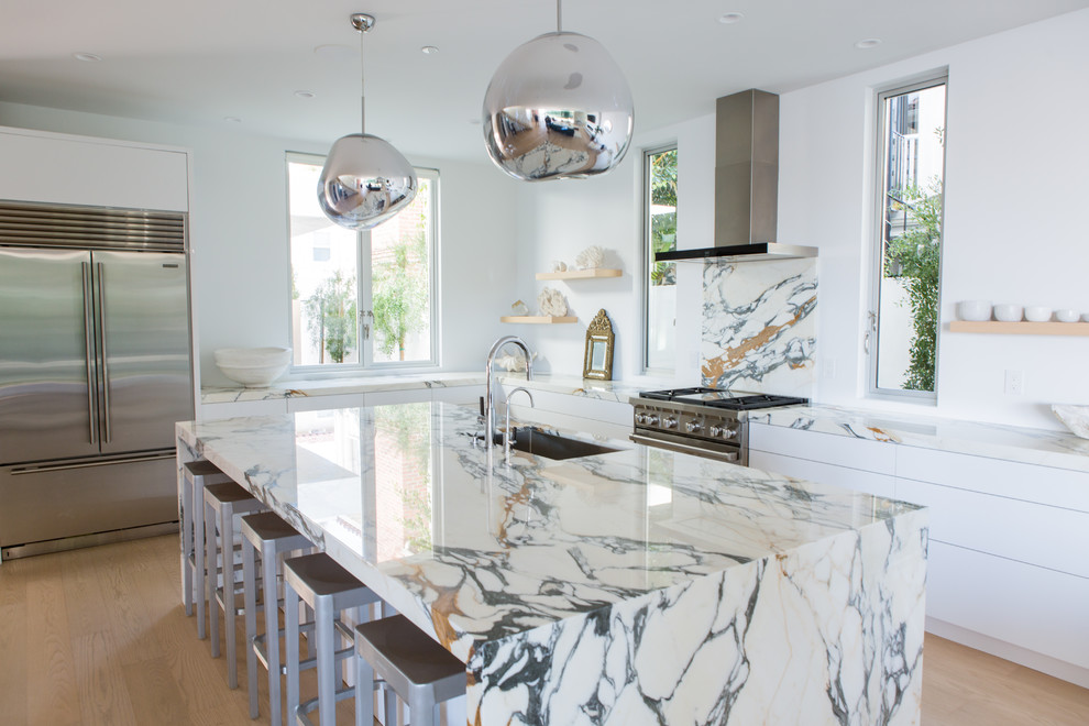 Kitchen - coastal l-shaped light wood floor and beige floor kitchen idea in Orange County with an undermount sink, flat-panel cabinets, white cabinets, marble countertops, multicolored backsplash, marble backsplash, stainless steel appliances, an island and multicolored countertops