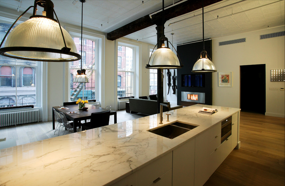Ispirazione per un cucina con isola centrale design con lavello sottopiano, ante lisce, ante bianche, top in marmo e parquet chiaro