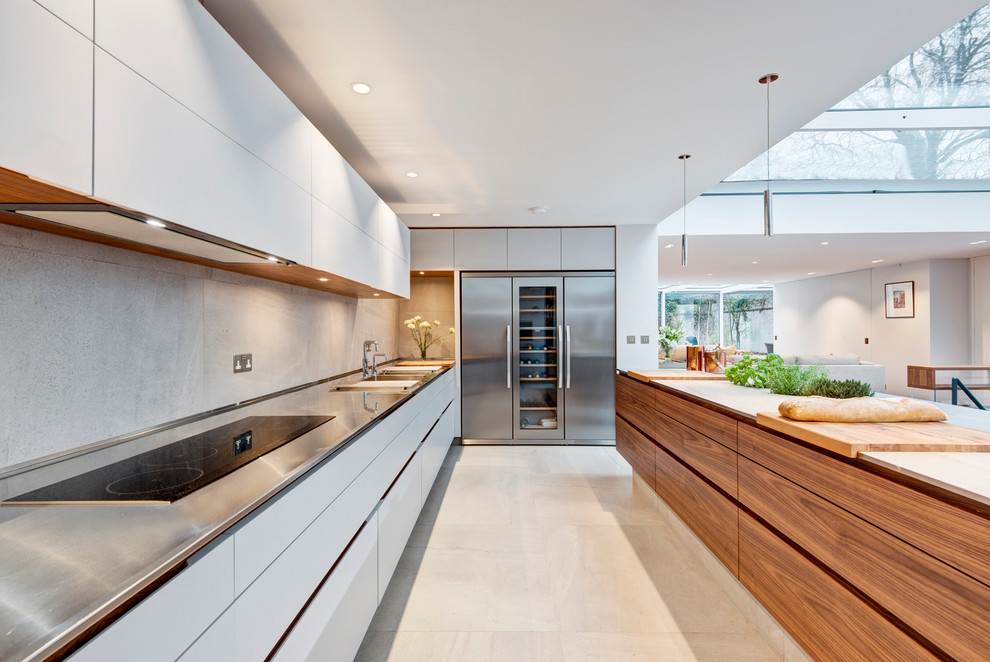 Offene Moderne Küche mit flächenbündigen Schrankfronten, weißen Schränken, Küchengeräten aus Edelstahl und Kücheninsel in London
