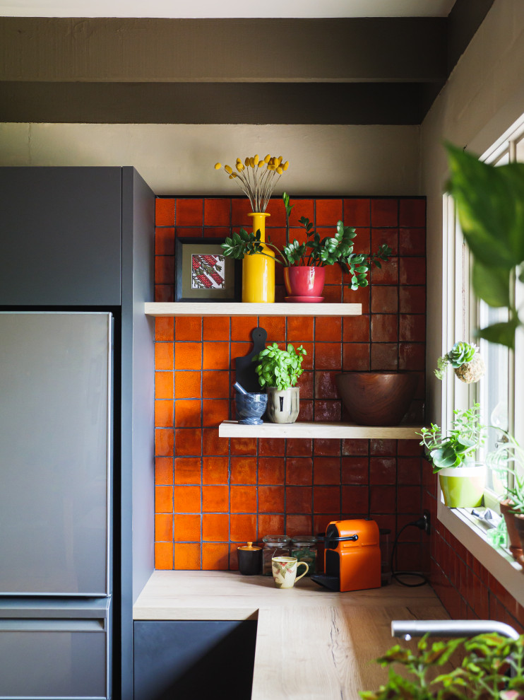 Inspiration för moderna kök, med en dubbel diskho, släta luckor, laminatbänkskiva, orange stänkskydd, stänkskydd i keramik, svarta vitvaror, mellanmörkt trägolv och en halv köksö