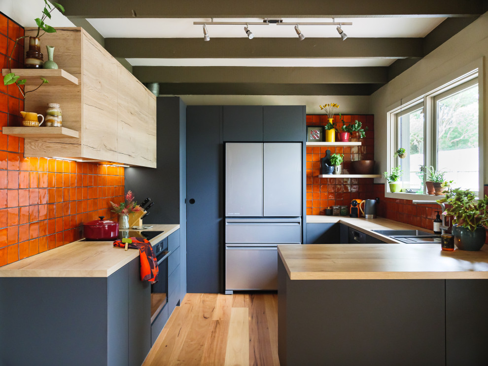 Idéer för mellanstora funkis kök, med en dubbel diskho, släta luckor, laminatbänkskiva, orange stänkskydd, stänkskydd i keramik, svarta vitvaror, mellanmörkt trägolv och en halv köksö