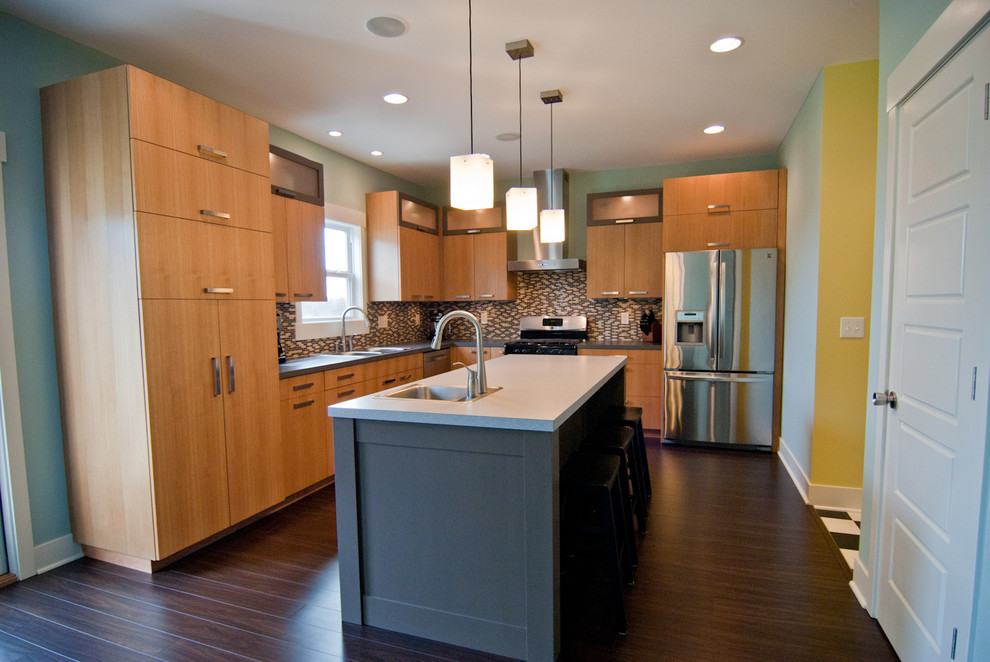 Foto på ett mellanstort funkis grå kök, med rostfria vitvaror, släta luckor, skåp i mellenmörkt trä, brunt stänkskydd, en nedsänkt diskho, bänkskiva i betong, stänkskydd i glaskakel, mörkt trägolv, en köksö och brunt golv