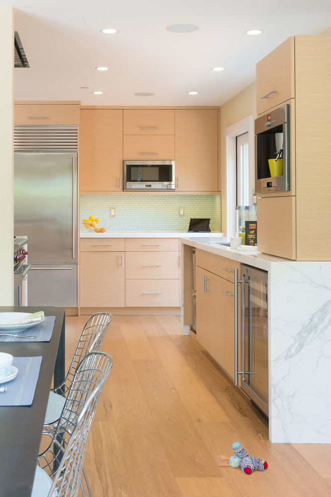 Bild på ett mellanstort funkis kök, med en undermonterad diskho, släta luckor, skåp i ljust trä, marmorbänkskiva, grått stänkskydd, stänkskydd i glaskakel, rostfria vitvaror, ljust trägolv och brunt golv