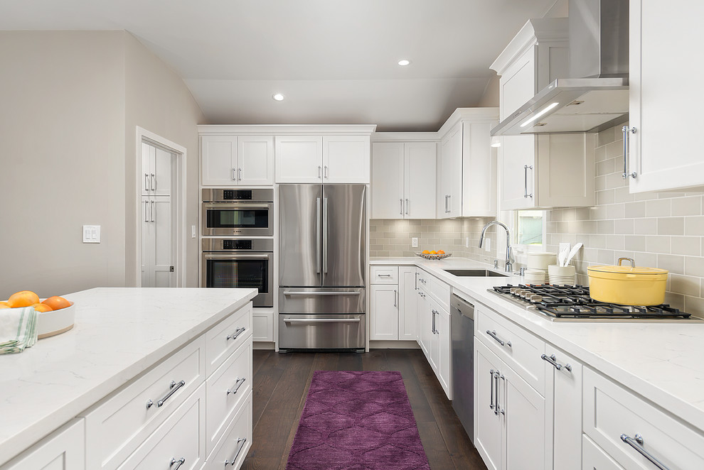 Example of a mid-sized trendy l-shaped dark wood floor and brown floor enclosed kitchen design in San Francisco with an undermount sink, shaker cabinets, white cabinets, quartz countertops, gray backsplash, subway tile backsplash, stainless steel appliances, an island and white countertops